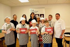 This photo shows the group of 6 children in the Junior Masterchef group, with three NCBI staff members and Neven Maguire. The children are all holding their certificates to mark the completion of the course. 